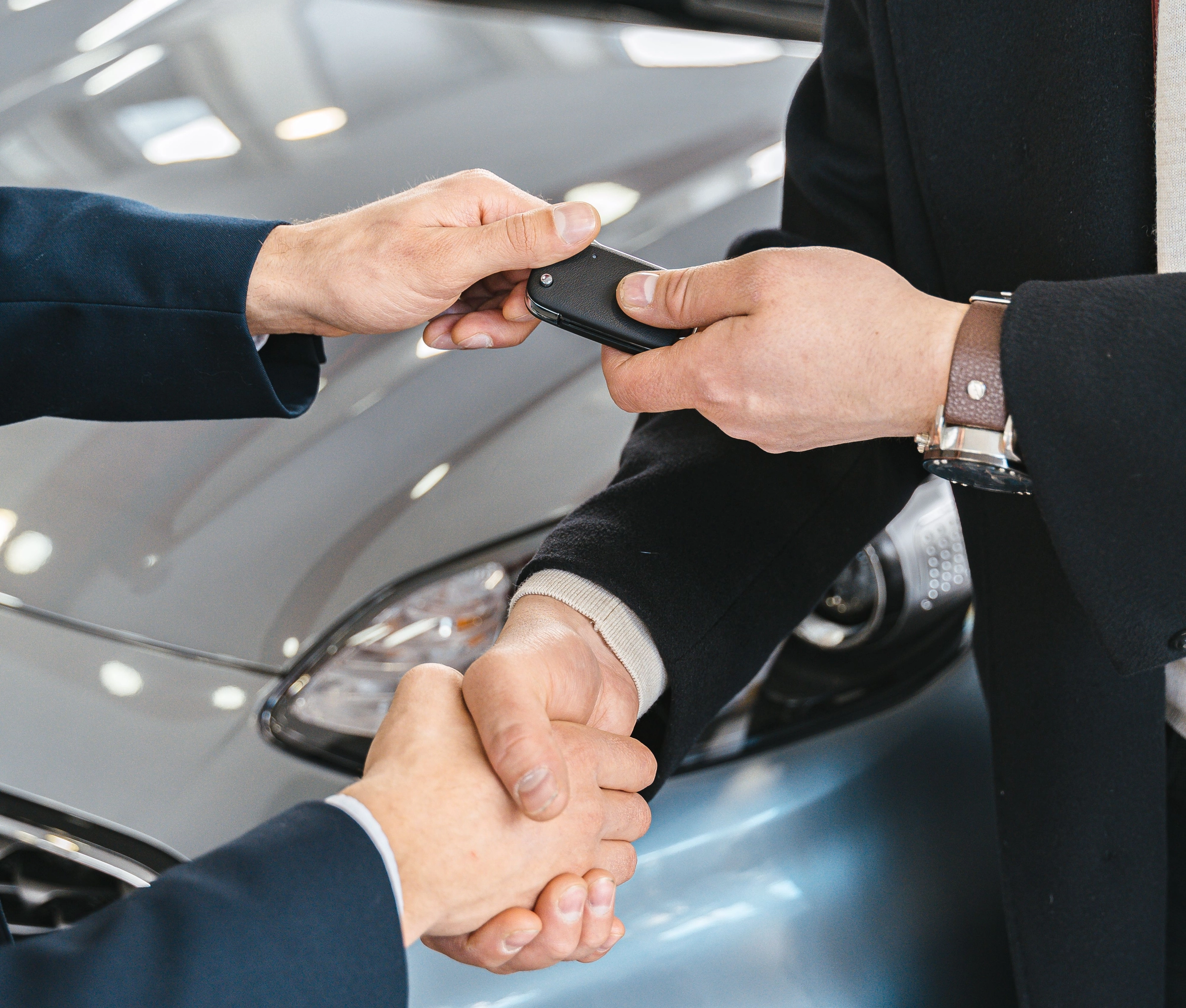 Handschlag und Schlüsselübergabe am Neuwagen im Autohaus